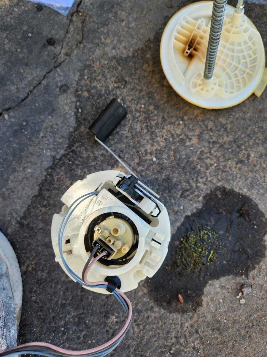 A fuel pump and sending unit laid out beside the car after removal